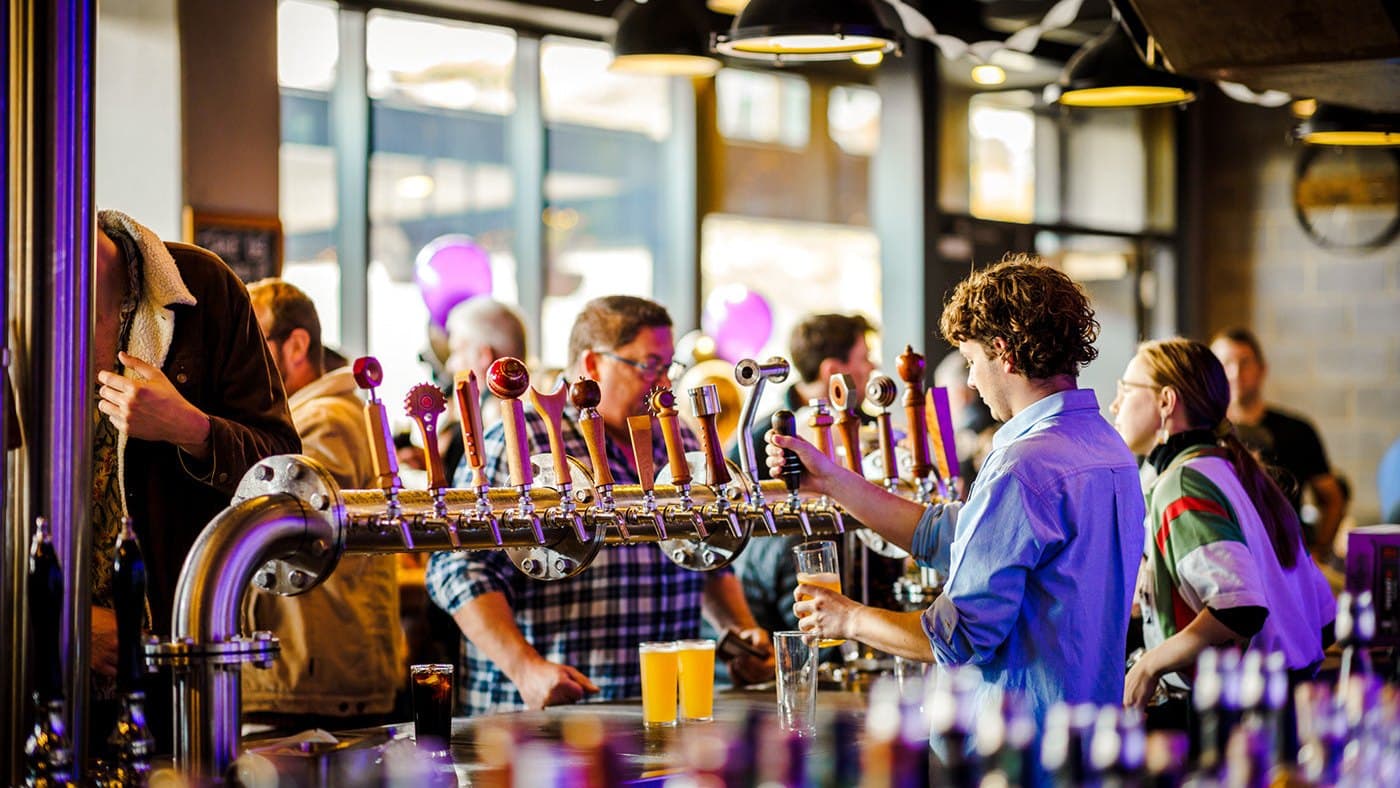 A bartender pouring a beer at the BentSpoke brewpub, in front of a row of taps