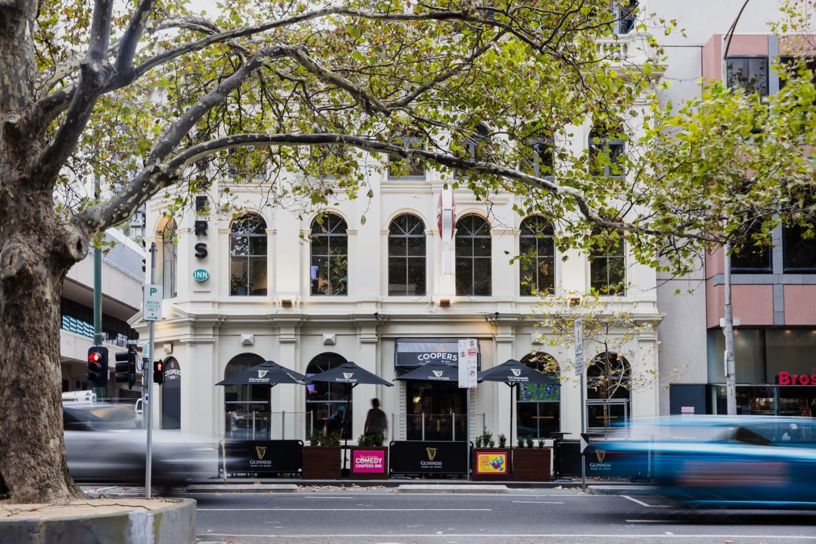 The heritage facade of the Coopers Inn in Melbourne's CBD, with arched windows and umbrellas on the footpath