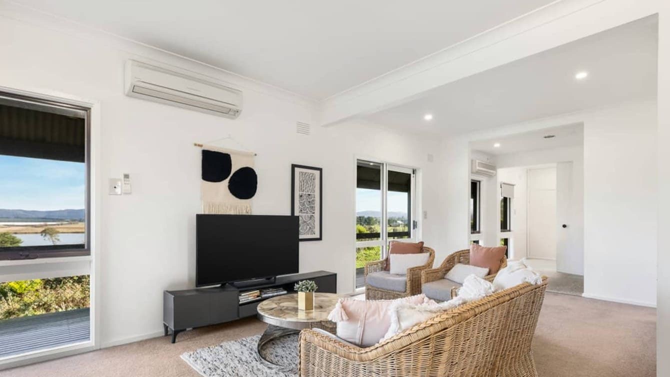 The living room of the Yarra Valley farmhouse, with wicker armchairs and windows looking out over the wetlands to the hills